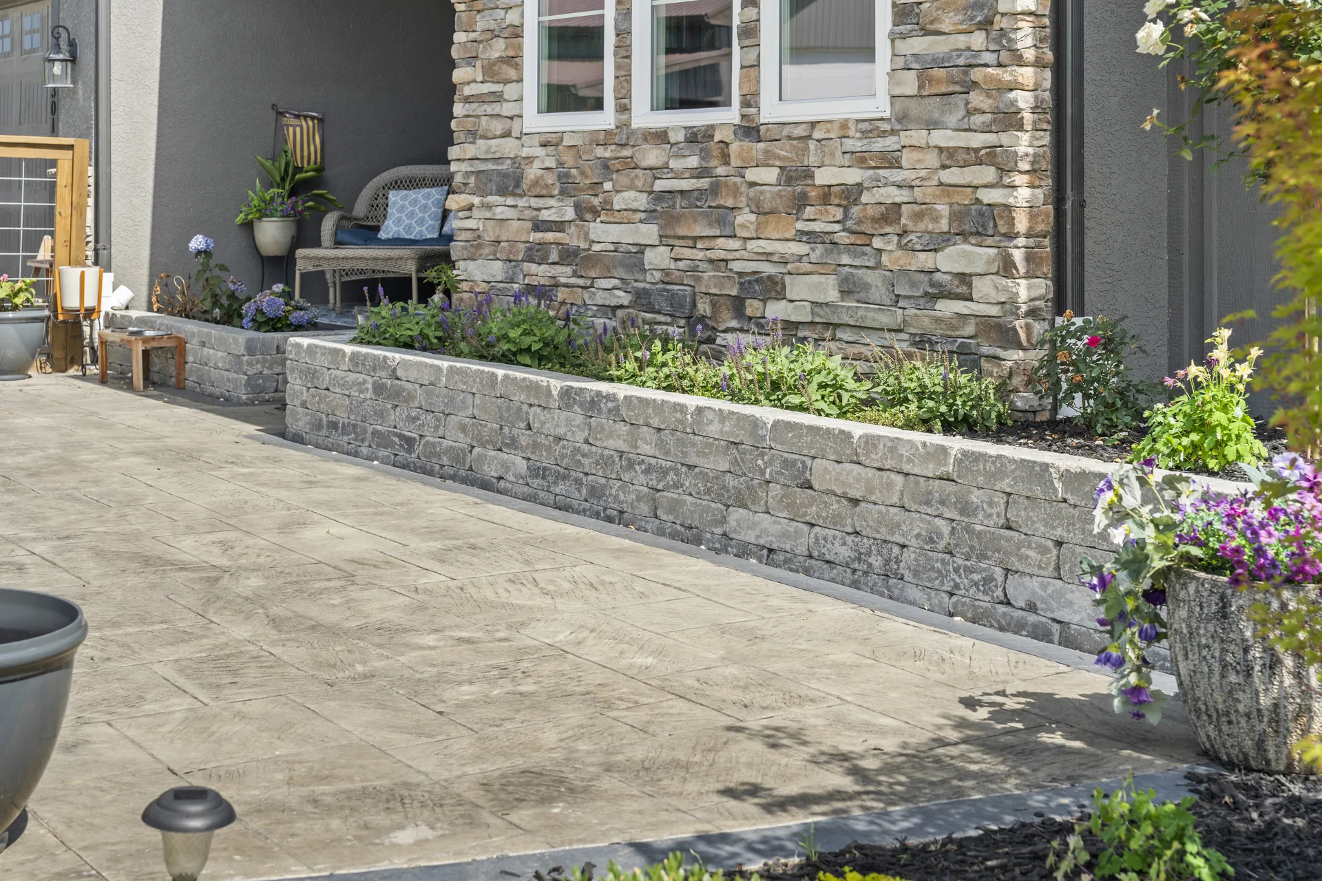 Raised stone planter beside the patterned pavers