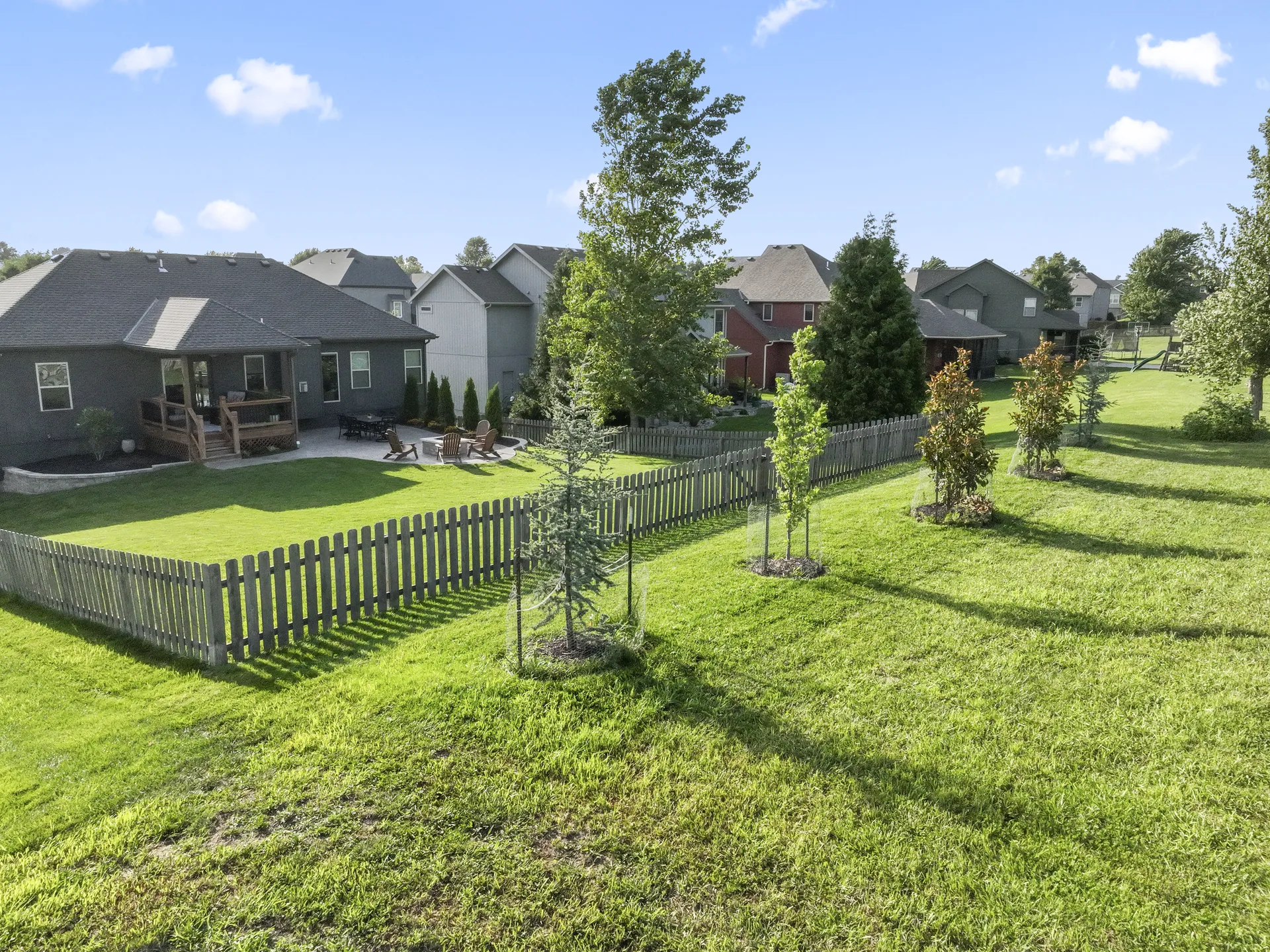 Fenced lawn and newly planted trees beyond the patio