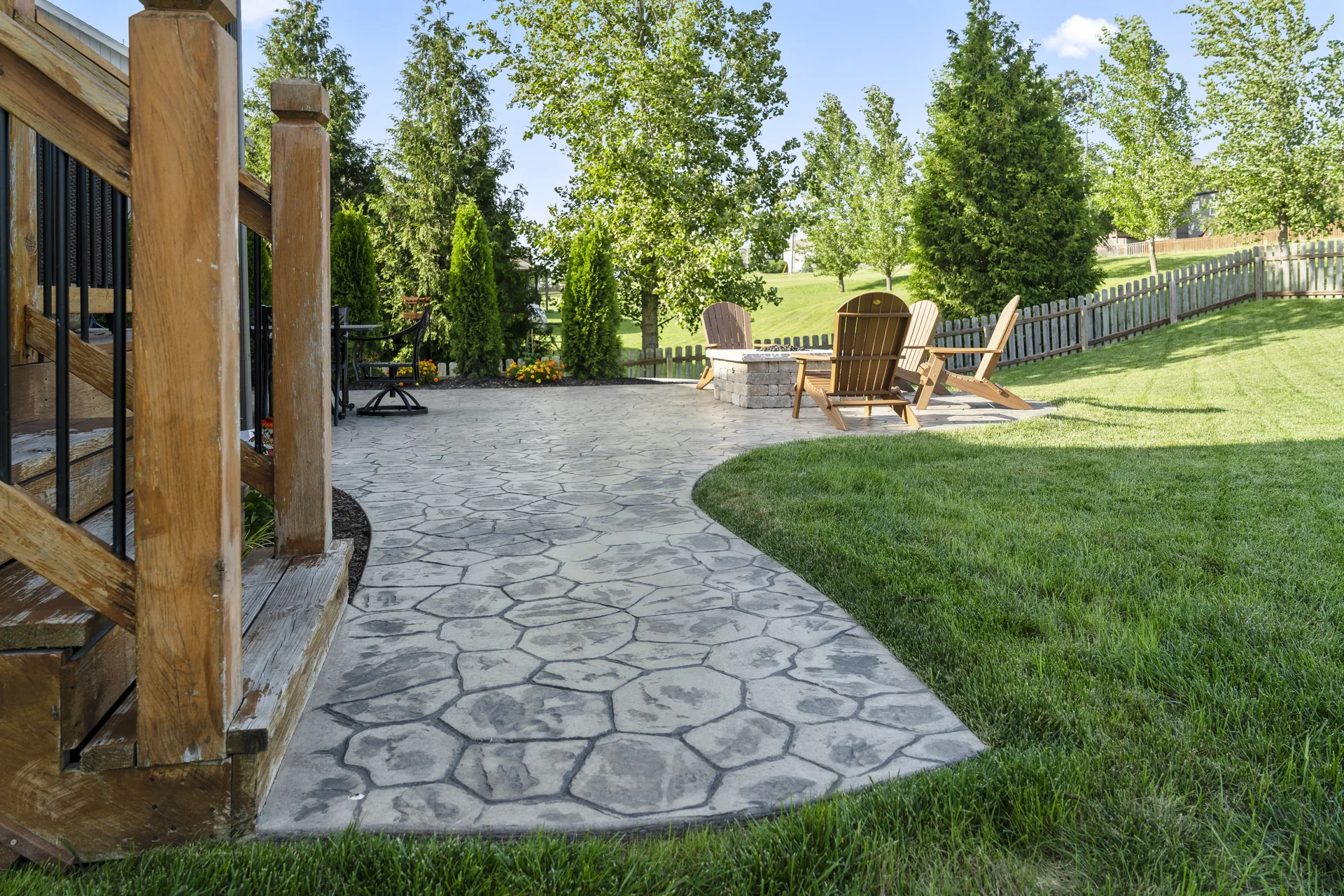 Curving paver walkway past shrubs toward the seating area