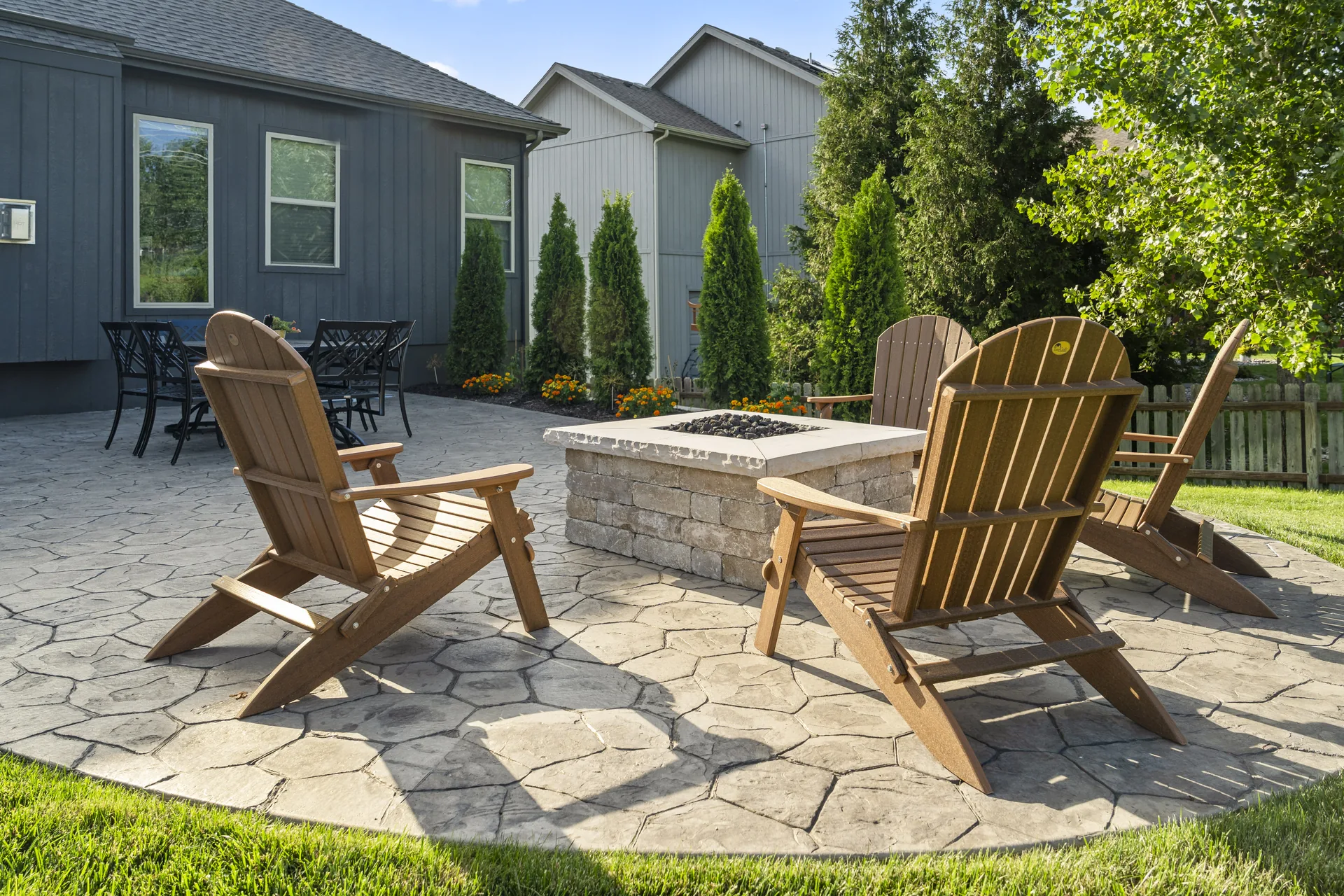 Paver patio with Adirondack chairs and a square fire pit