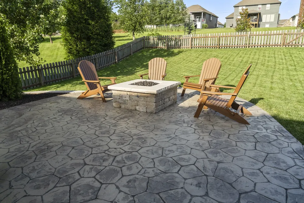 Square stone fire pit with chairs on a paver patio