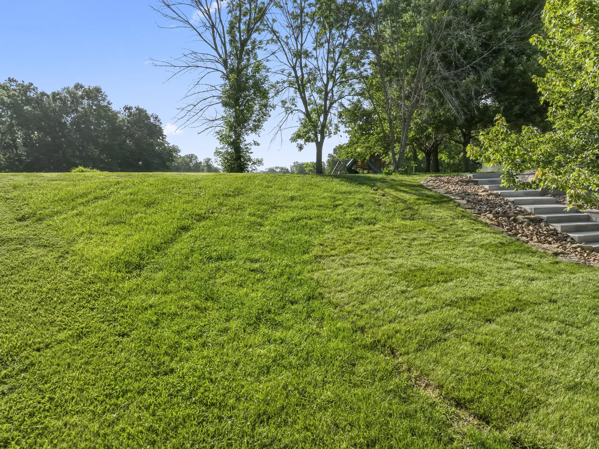 Open lawn and stone-edged landscape bed on the slope