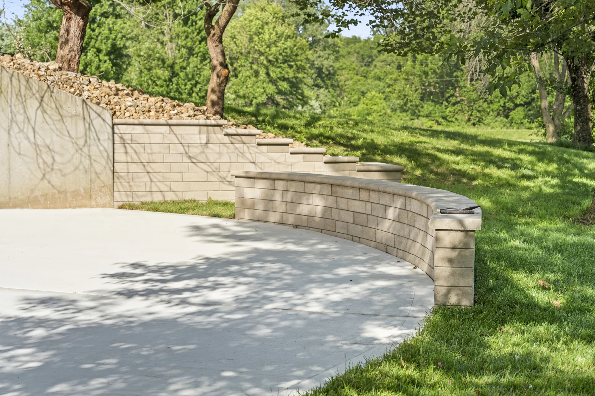 Curving wall enclosing a planting area beside the patio