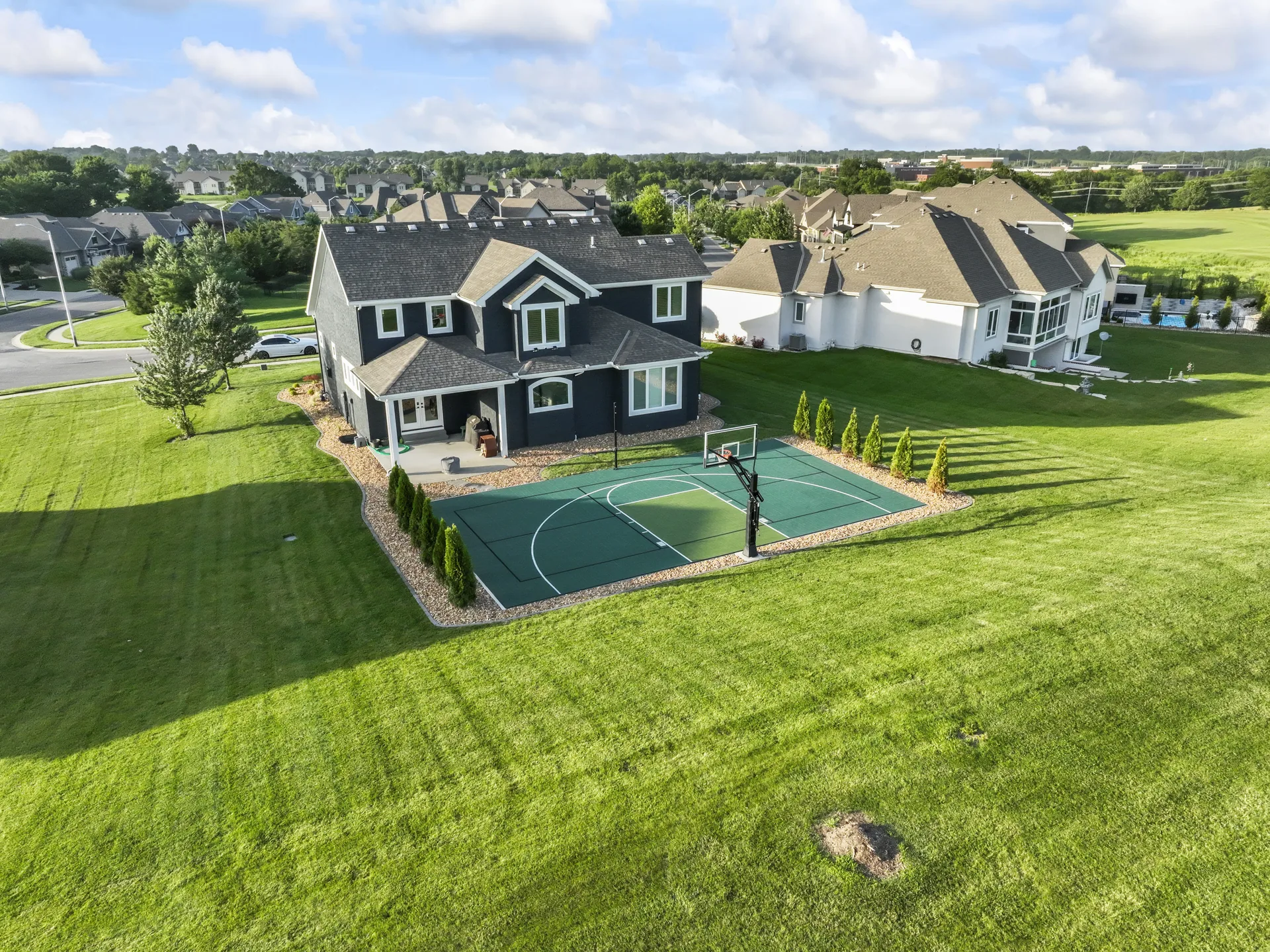 Wide aerial view of the basketball court behind the house