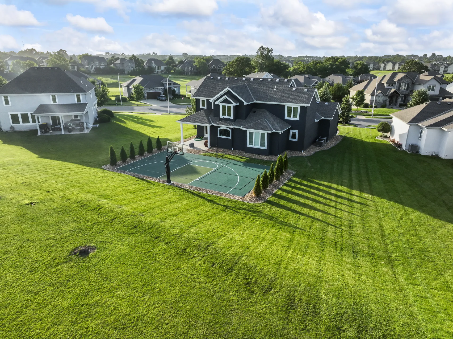 Backyard court with two hoops and lawn beyond