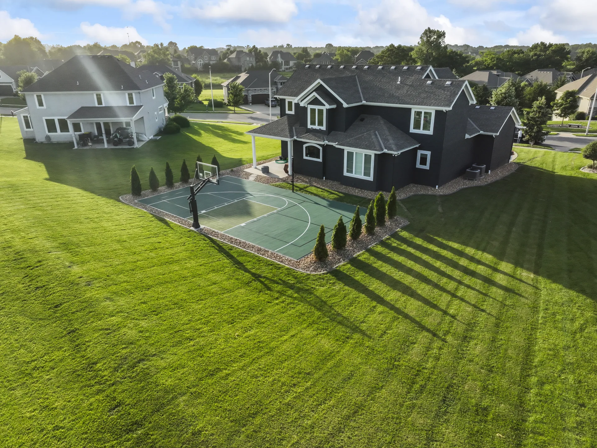 Angled aerial view of the court, home and tree line