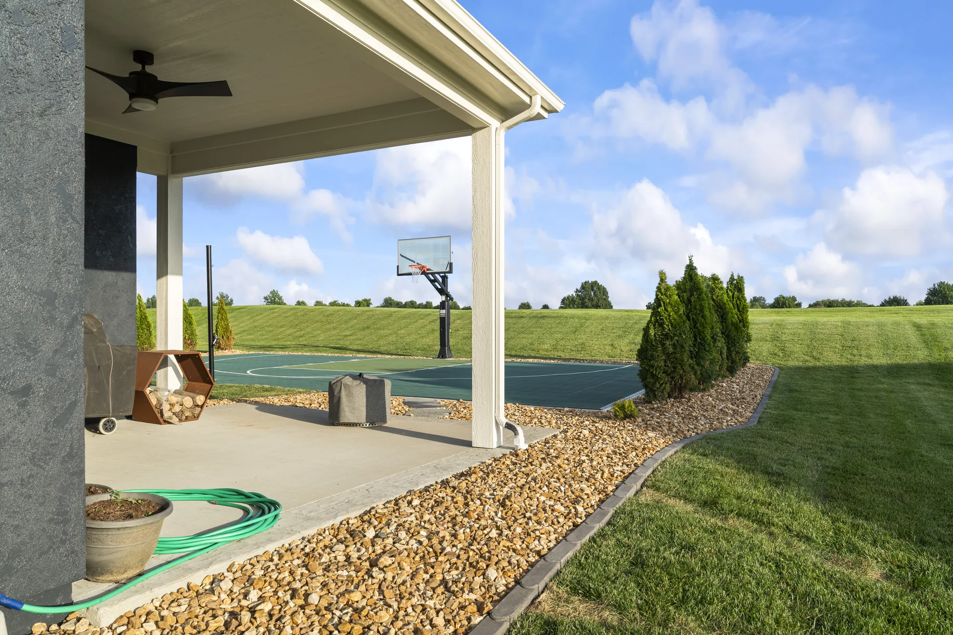 Covered patio with stone edging beside the sport court
