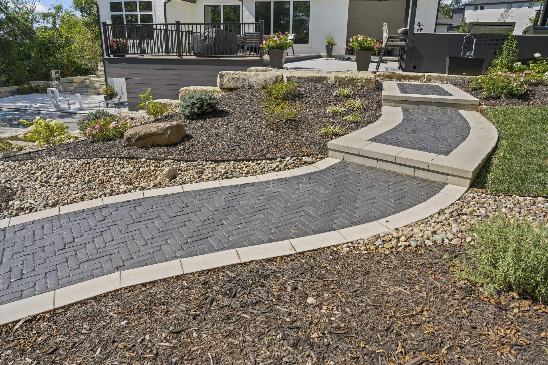S-shaped paver path bordered by landscape stone