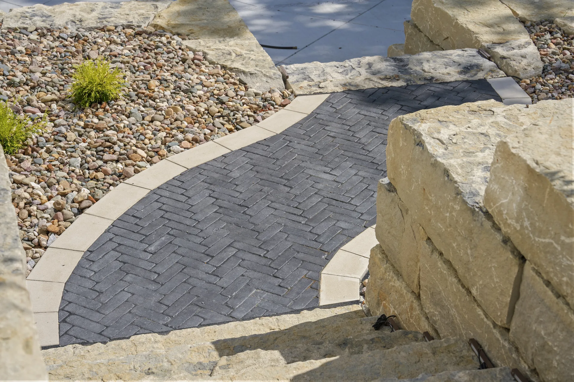 Paver path with a smooth border beside river rock