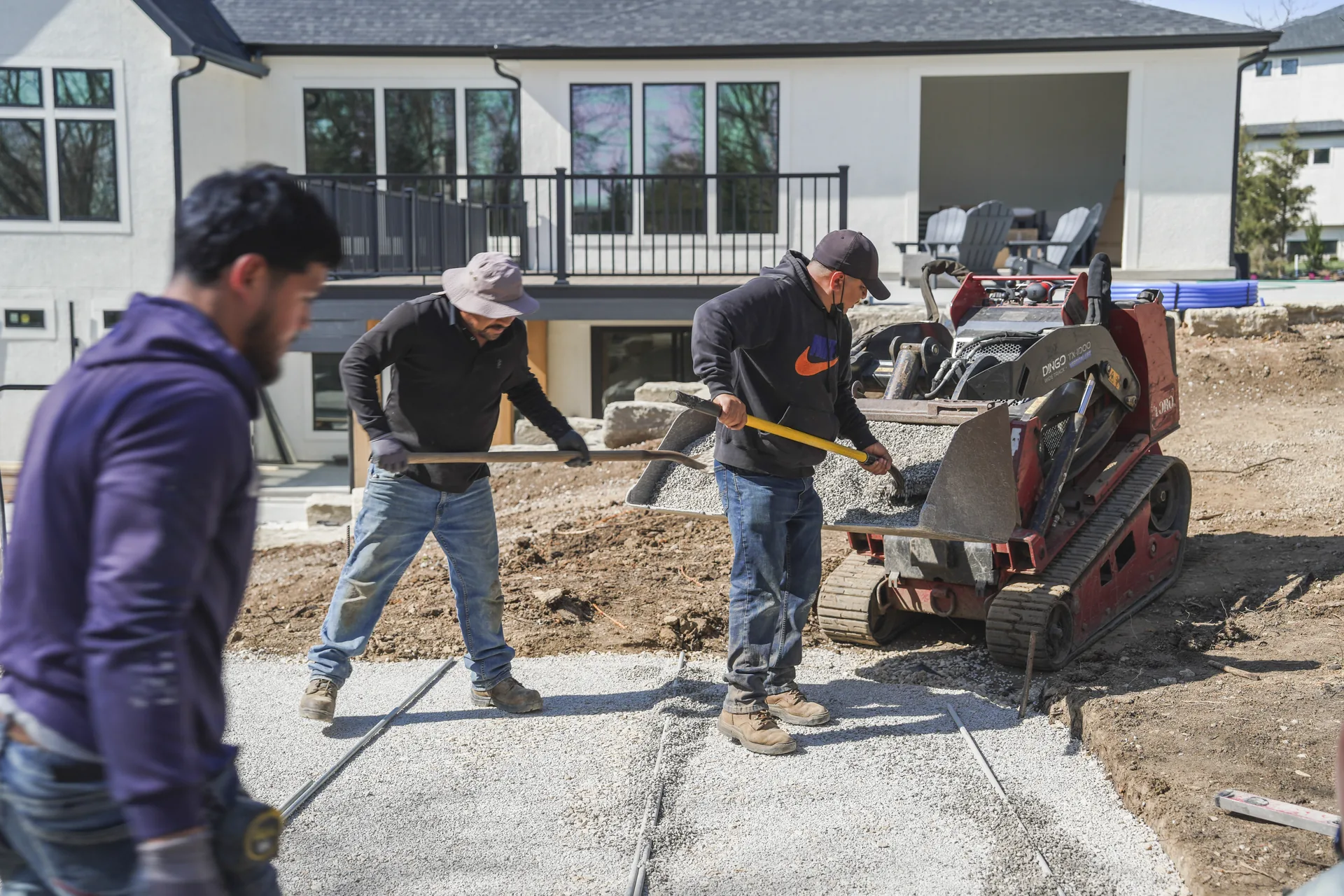 Workers setting pavers in the area beside the home