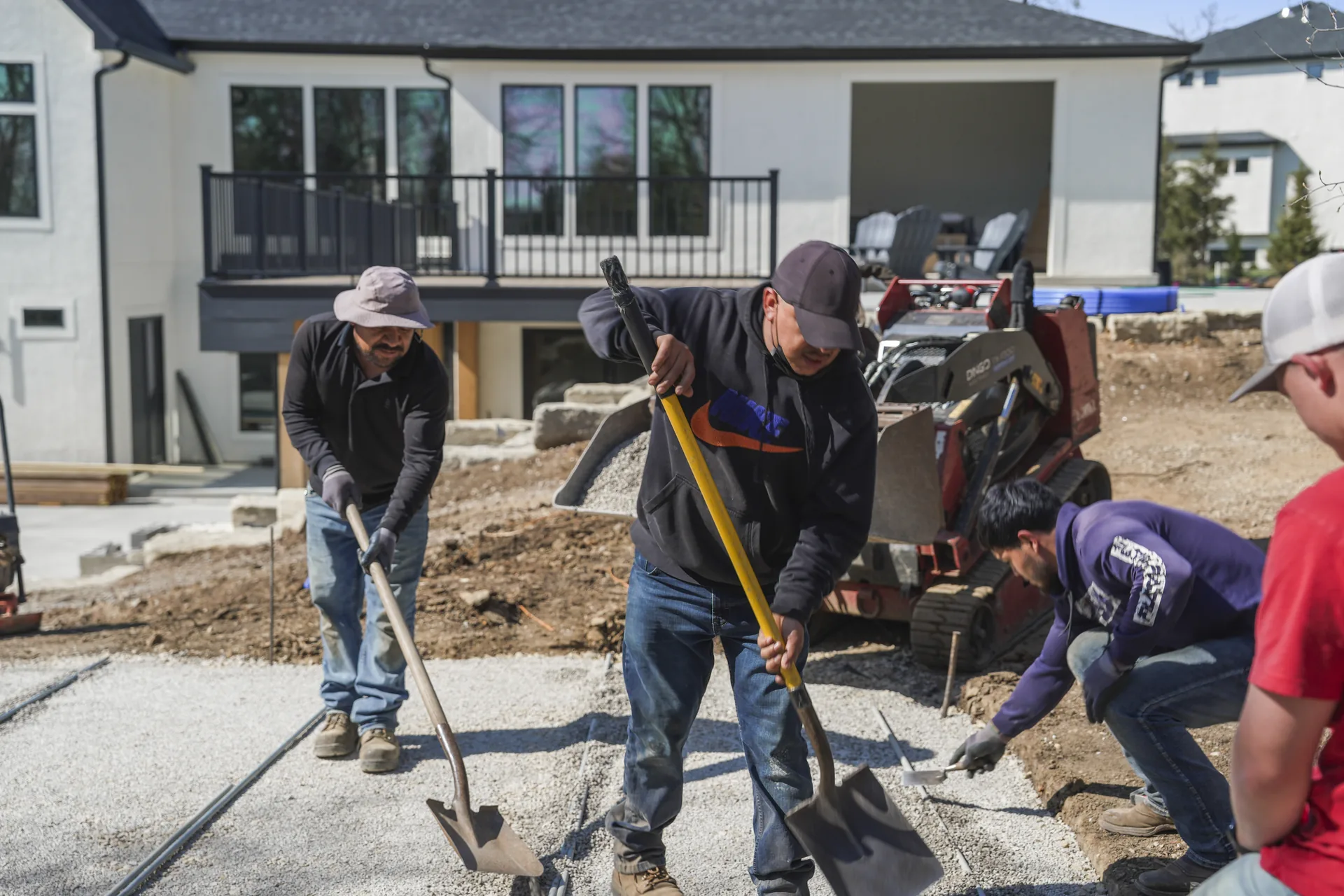 Crew aligning pavers at the edge of the work area