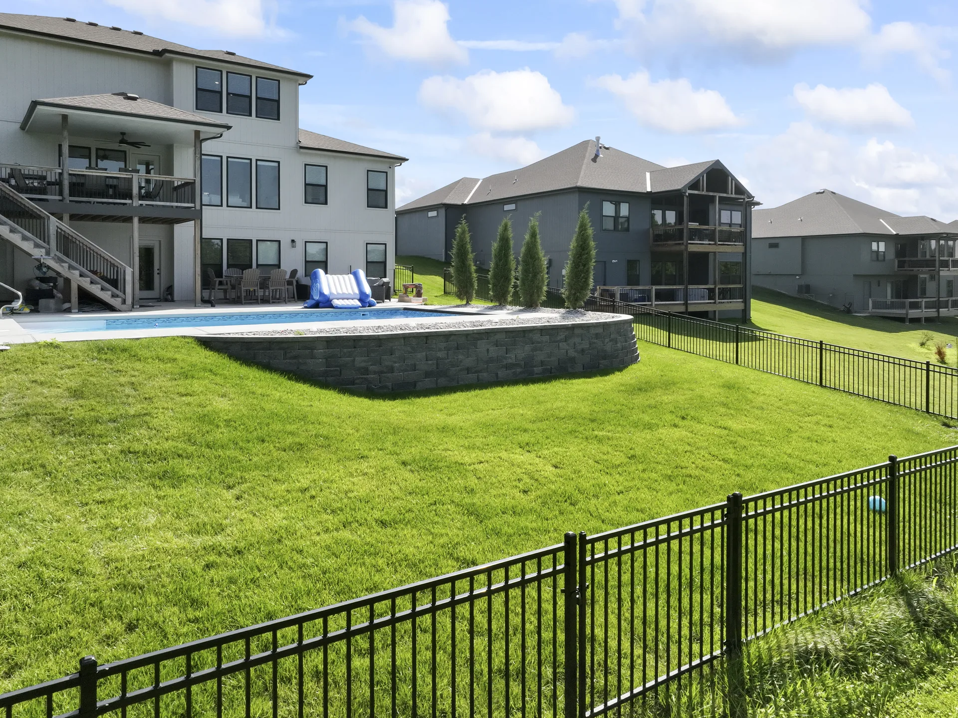 Wide view of the pool and sloping lawn