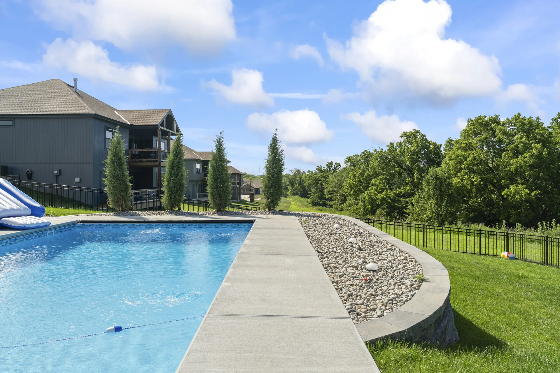 Curved pool deck overlooking the fenced lawn
